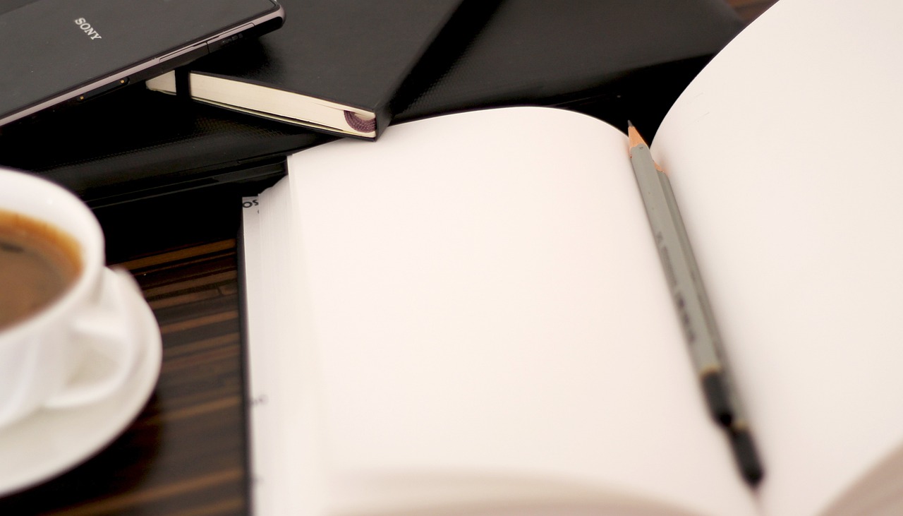 An open book on a table with a pen in it.